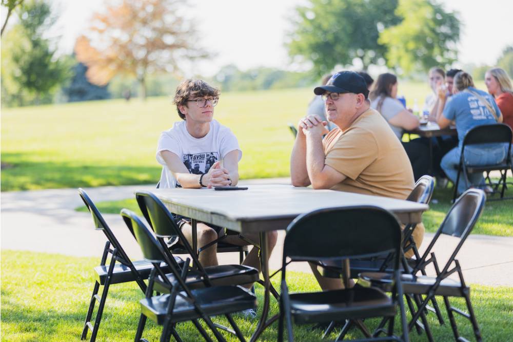 Family talking at table on Kirkhof Lawn.